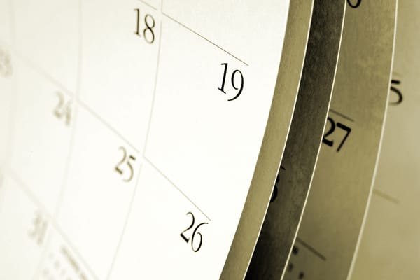 A blank calendar at an artistic angle, with a close-up on the right edge of the calendar, but with months of pages visible tucked behind.